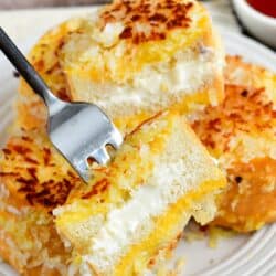 sliced coconut stuffed French toast on a fork and more on the plate.