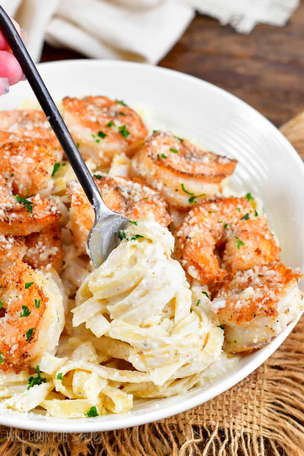 Shrimp Alfredo in a bowl and swirling some of the pasta onto a fork.