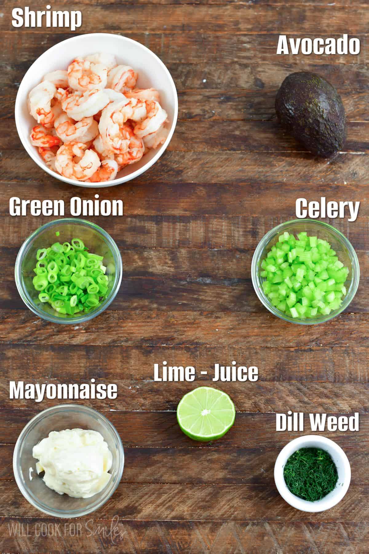 Labeled ingredients for shrimp salad on a wood surface.