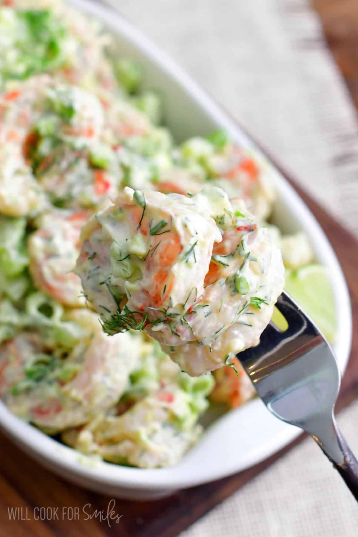 Shrimp salad in a serving dish with some on a fork.