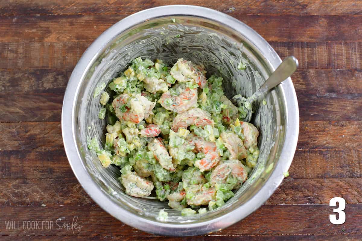 Shrimp Salad ingredients mixed up in a metal bowl with a metal spoon.
