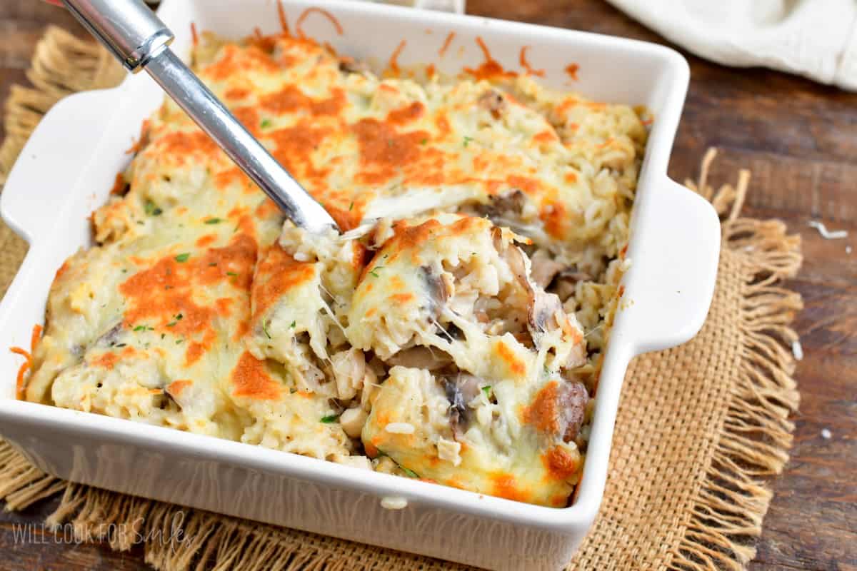 Scooping some of the chicken mushroom rice casserole with a big spoon.