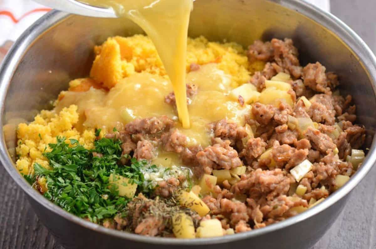 adding egg mixture to the cornbread dressing ingredients in the bowl.