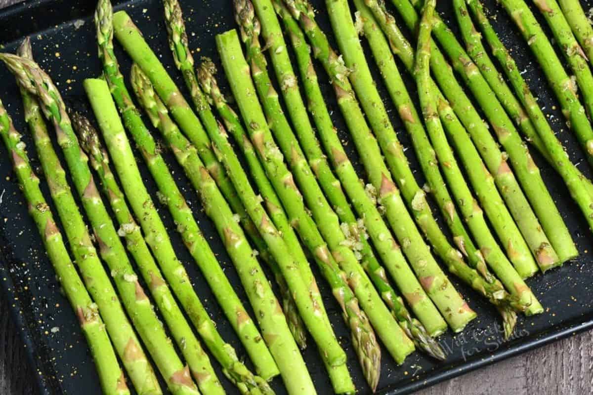 asparagus stalks spread in the baking sheet before cooking.