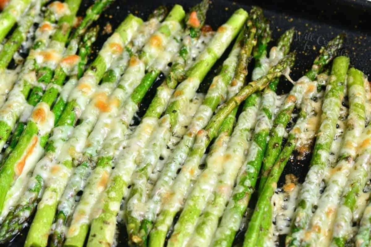 roasted asparagus with parmesan cheese and italian seasoning spread in baking sheet.