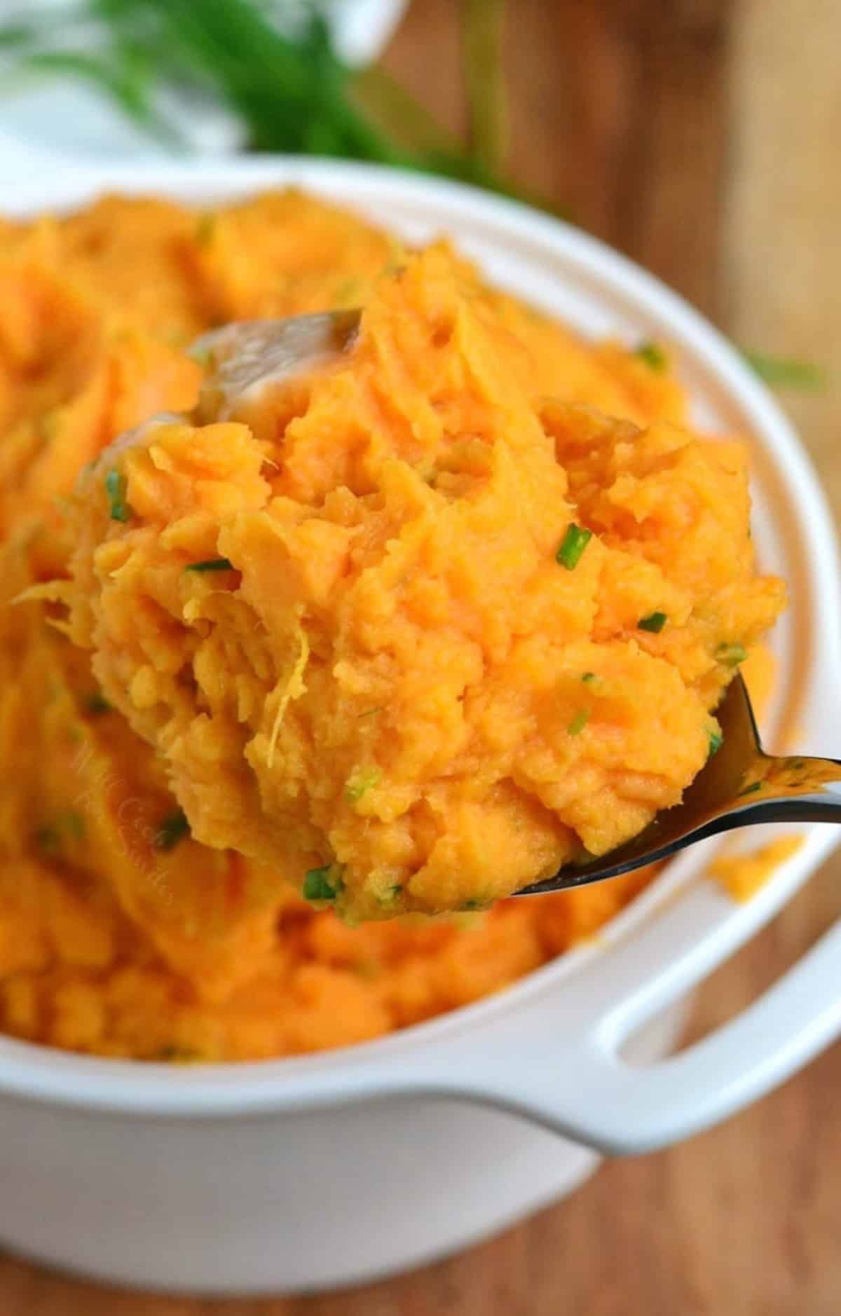 scooping out a ladleful of sweet mashed potatoes from the bowl.