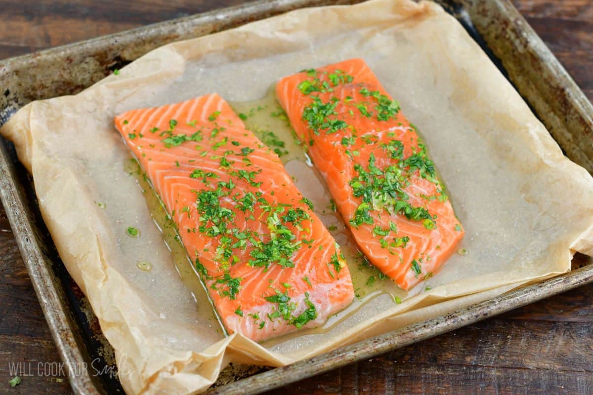 two salmon filets in cilantro honey lime sauce on a baking sheet.