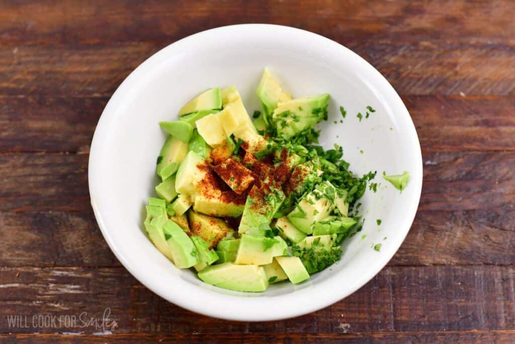 seasoning avocado pieces in a bowl for the salmon rice bowl.