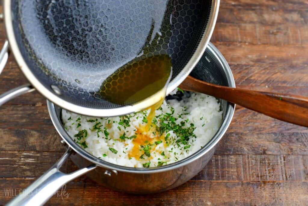 pouring in sweet sauce into cilantro rice for salmon rice bowl.