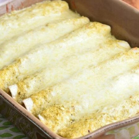 several enchiladas baked in verdes sauce and cheese on top.