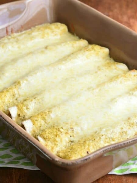 several enchiladas baked in verdes sauce and cheese on top.