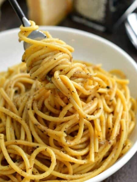 swirling some cheesy cacio e pepe pasta onto the fork from the bowl.
