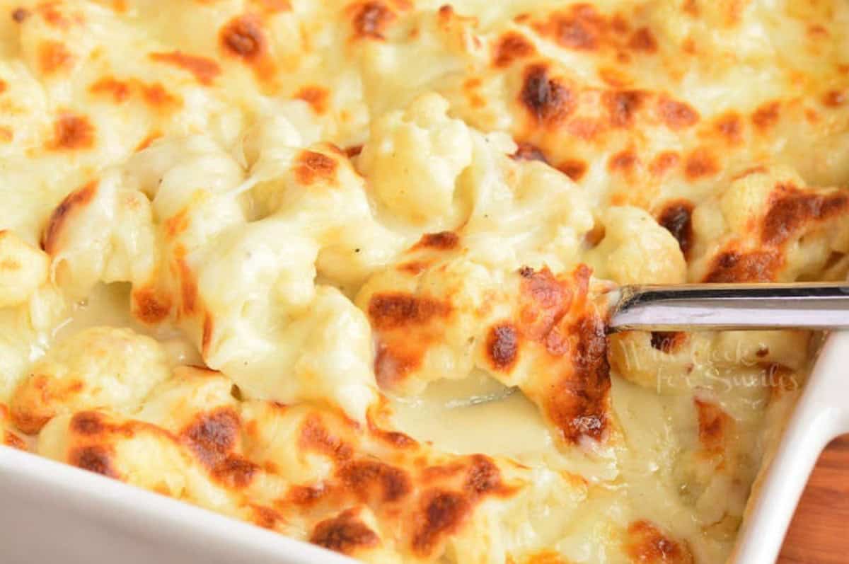 Scooping up cauliflower mac and cheese with a metal spoon.