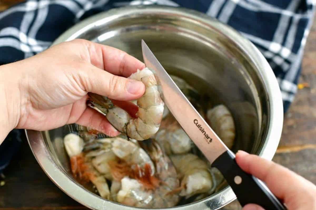 Cutting into a shrimp to devein it with a knife.