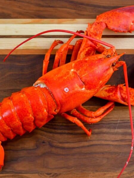 whole cooked lobster lain down on a wooden cutting board.