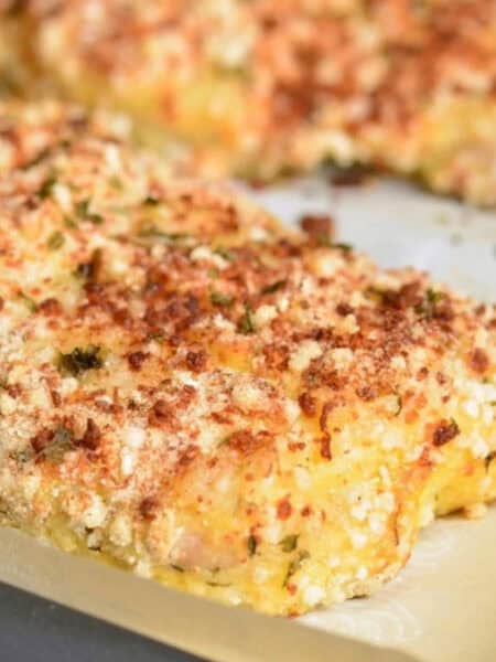 crispy parmesan crusted piece of mahi mahi on parchment paper covered baking sheet.