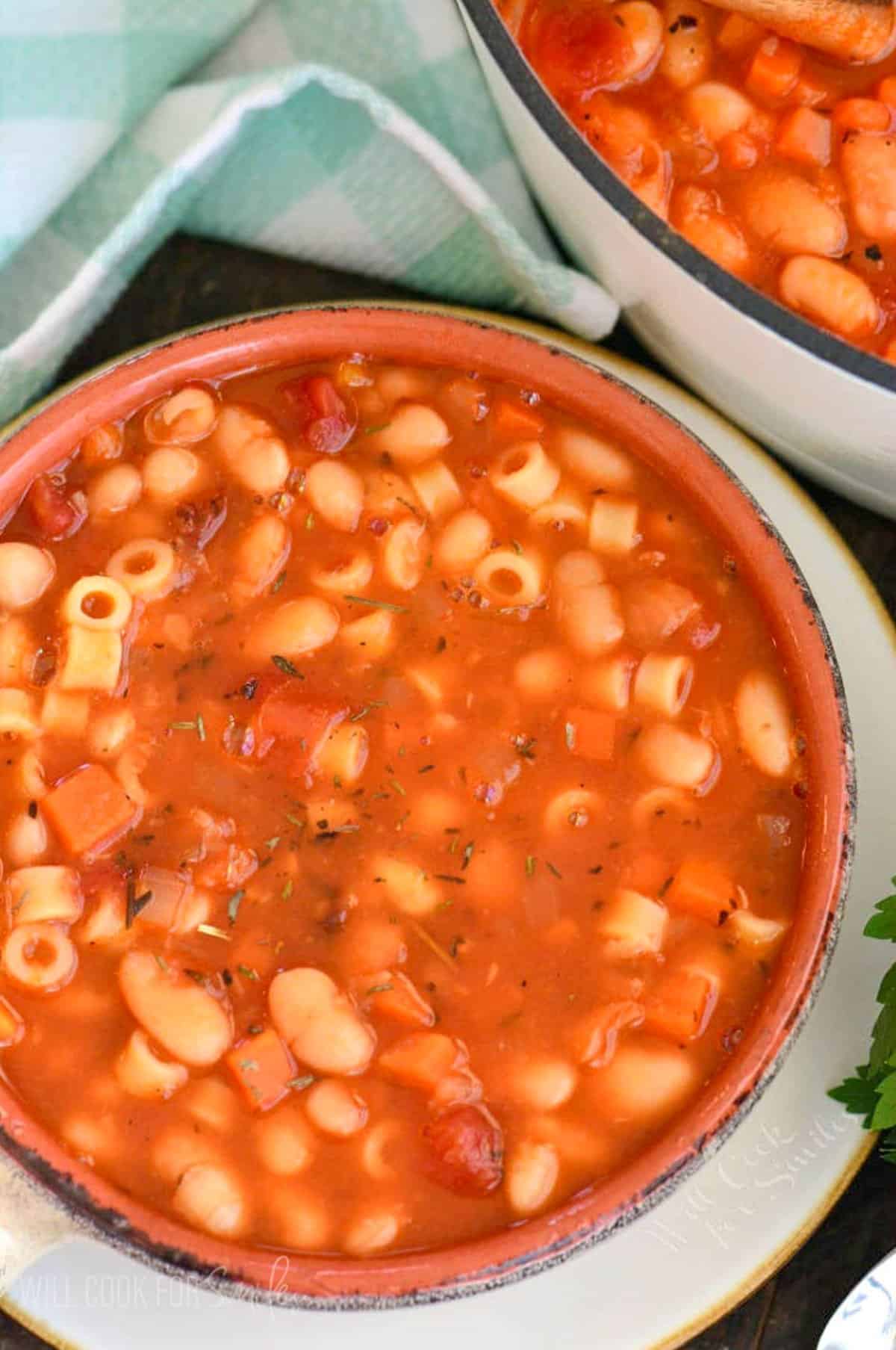 pasta e fagioli in a rustic bowl next to the pot on soup.