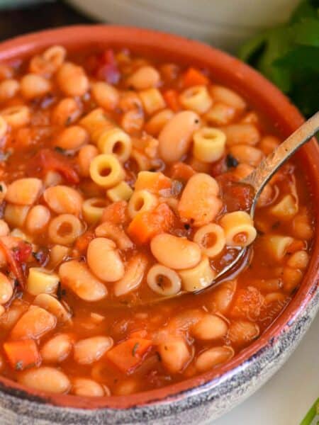 spooning out some pasta e fagioli soup from the bowl.