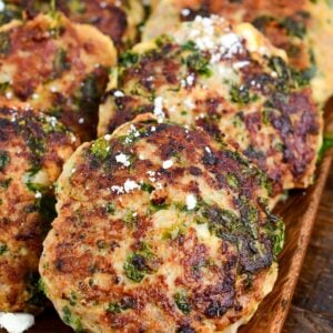 cooked turkey burgers laid out on the platter topped with a little feta cheese.