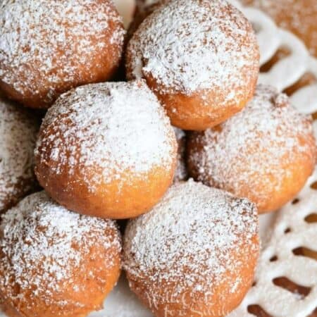 stacked ricotta donuts on a plate with powdered sugar.