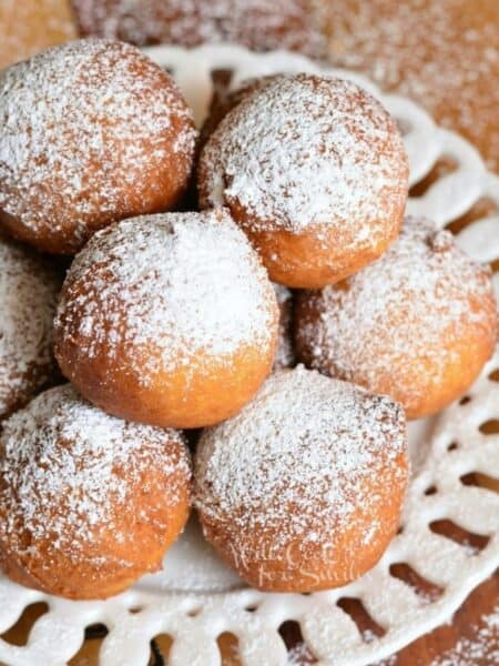 stacked ricotta donuts on a plate with powdered sugar.