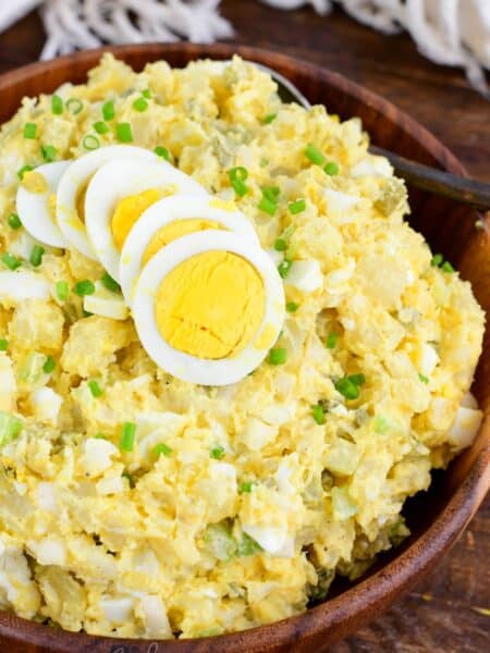 potato salad with eggs, pickles, and creamy mustard sauce in a bowl topped with egg.