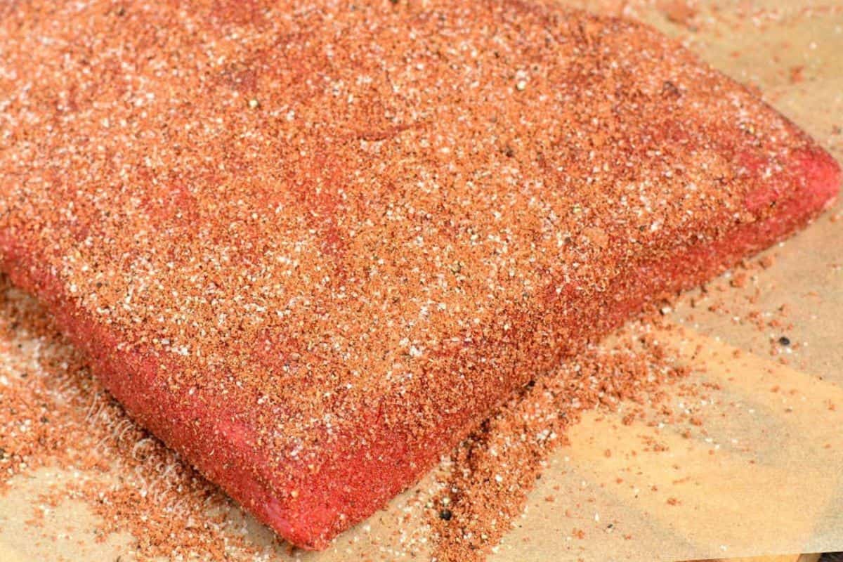 beef brisket flat coated in the dry rub seasoning on parchment paper.