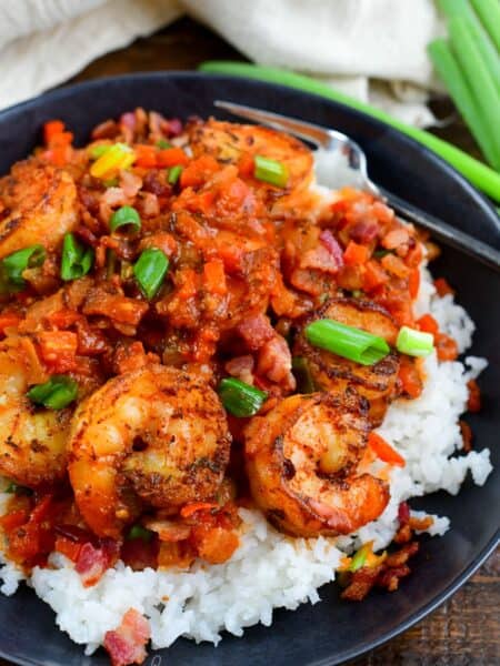 Cajun shrimp over rice in a bowl on a wood surface.