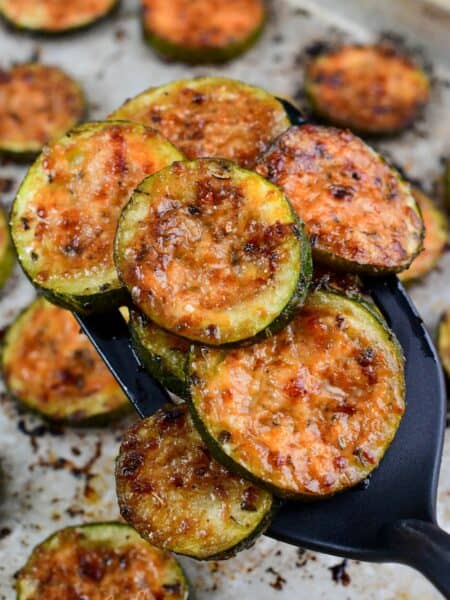 roasted zucchini on a spatula with the rest on a baking sheet.