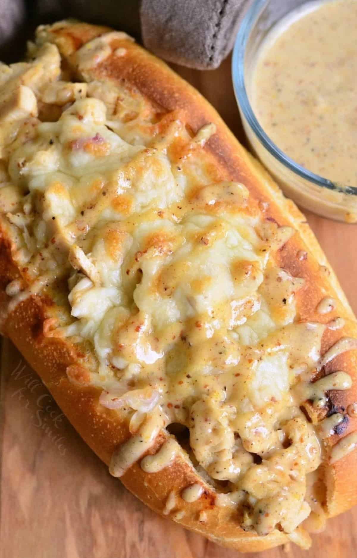 baked chicken sub sandwich packed with diced chicken, melted cheese, and white BBQ sauce on top.