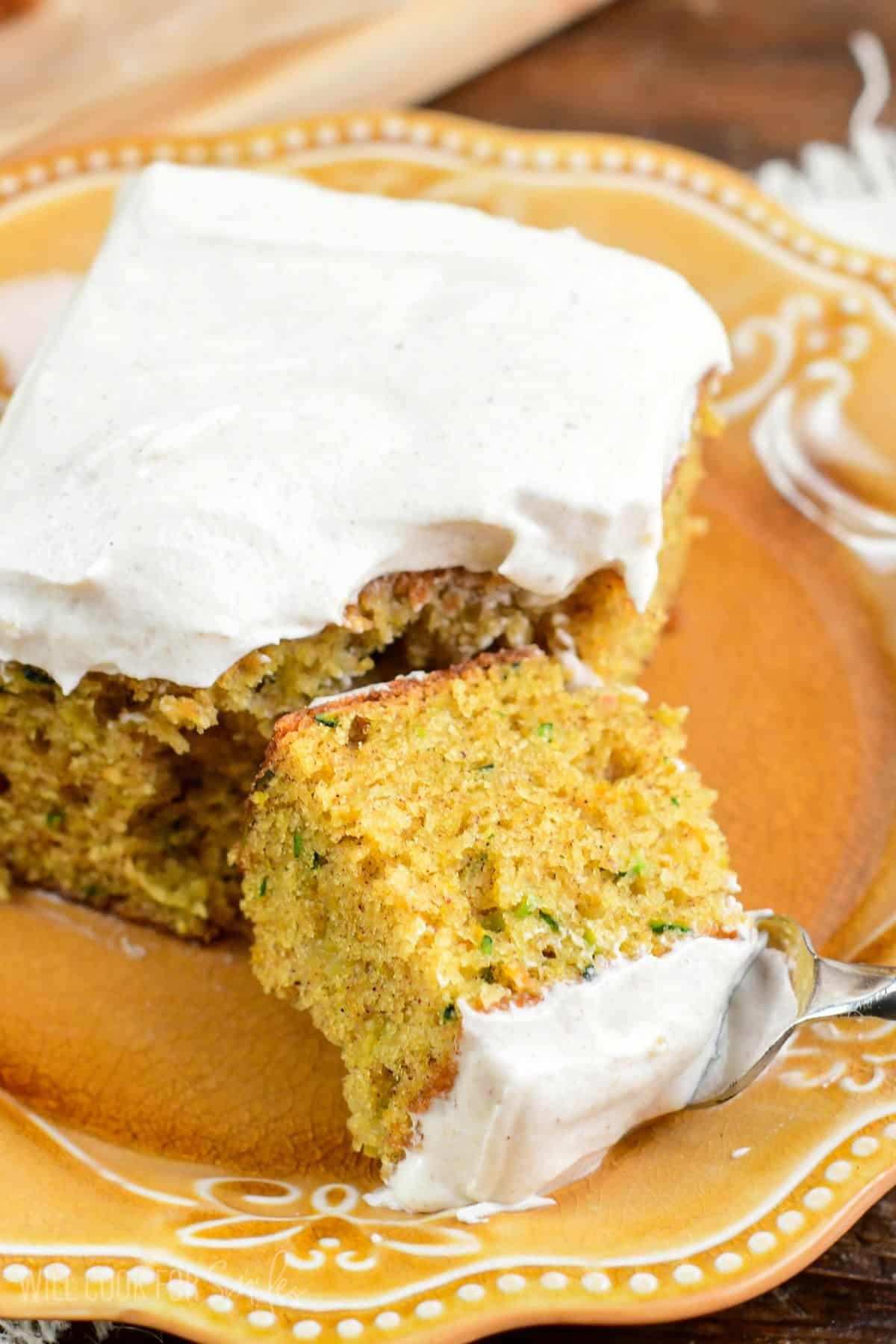 Zucchini cake on a plate with a slice of it on a fork.