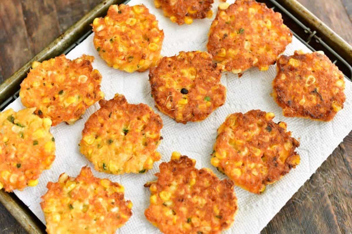 several cooked corn fritters laid out on the paper towel.