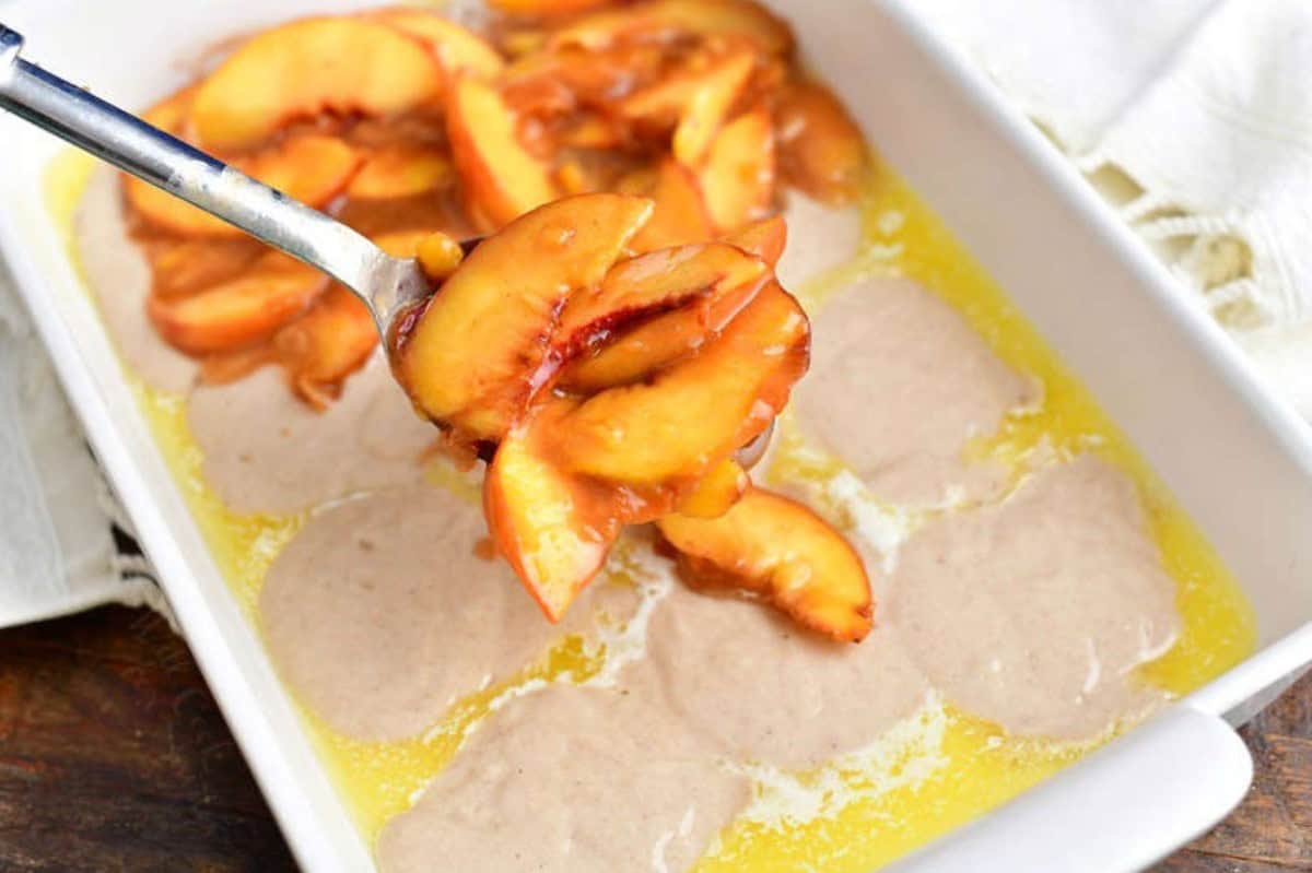 adding cooked peaches to the batter in the baking dish.