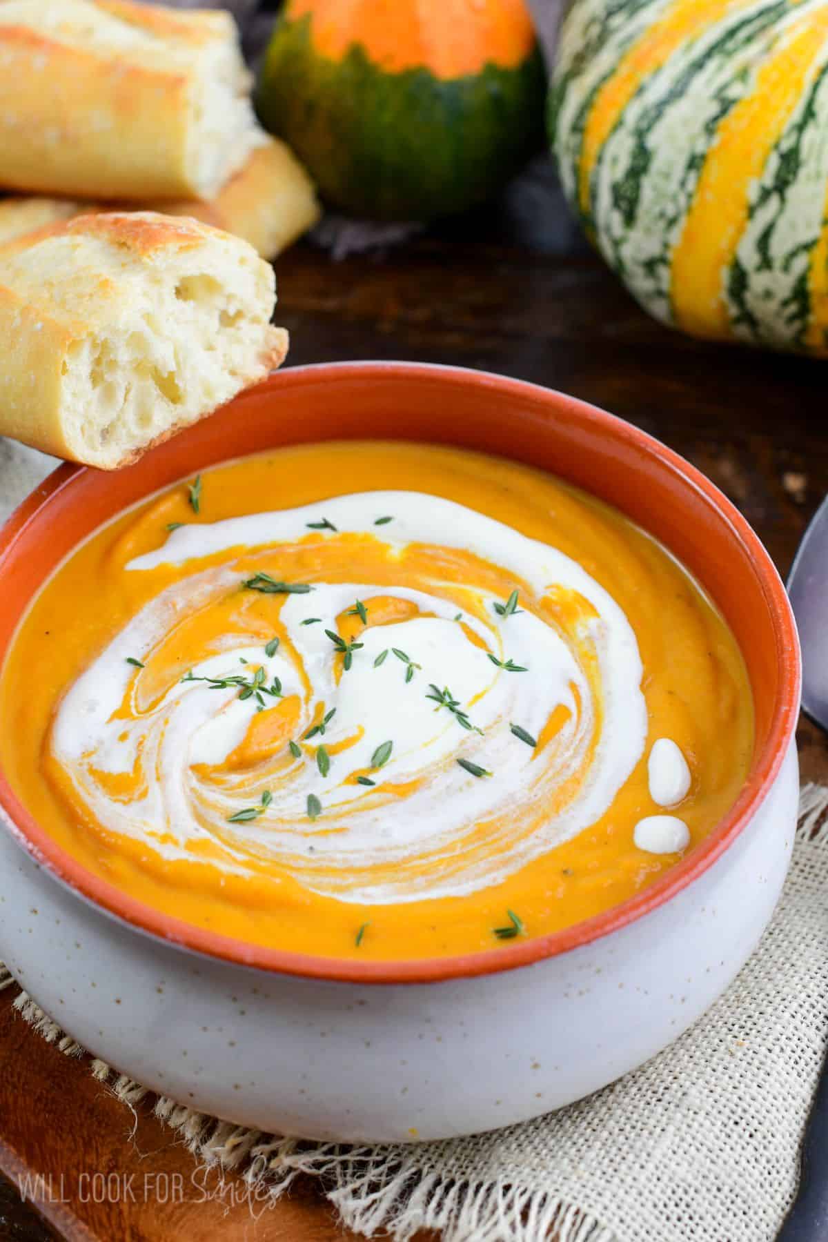 Pumpkin soup in a bowl with cream drizzled over the top.