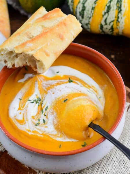 starting to spoon out some pumpkin soup drizzled with cream.