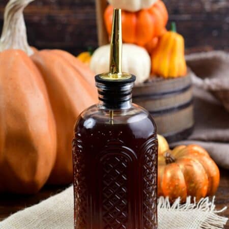 pumpkin spice syrup in a glass container on a wood table.