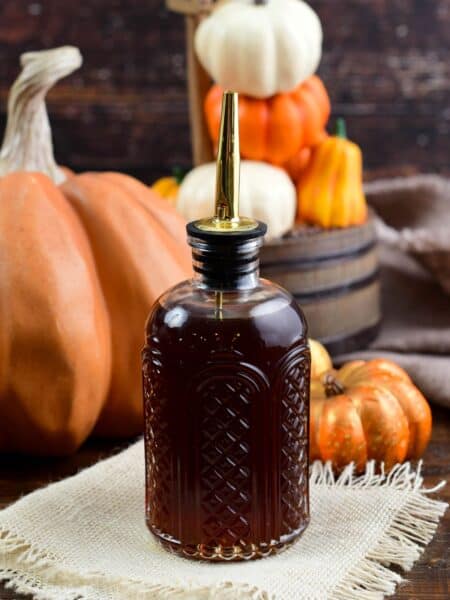 pumpkin spice syrup in a glass container on a wood table.
