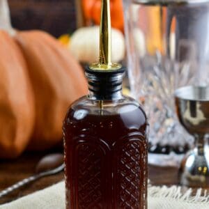 pumpkin spice syrup in a glass jar with pumpkins in the background.