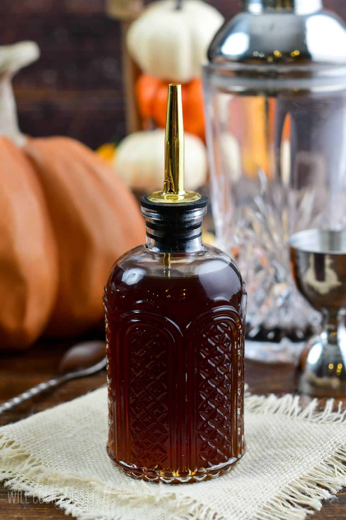 pumpkin spice syrup in a glass jar with pumpkins in the background.