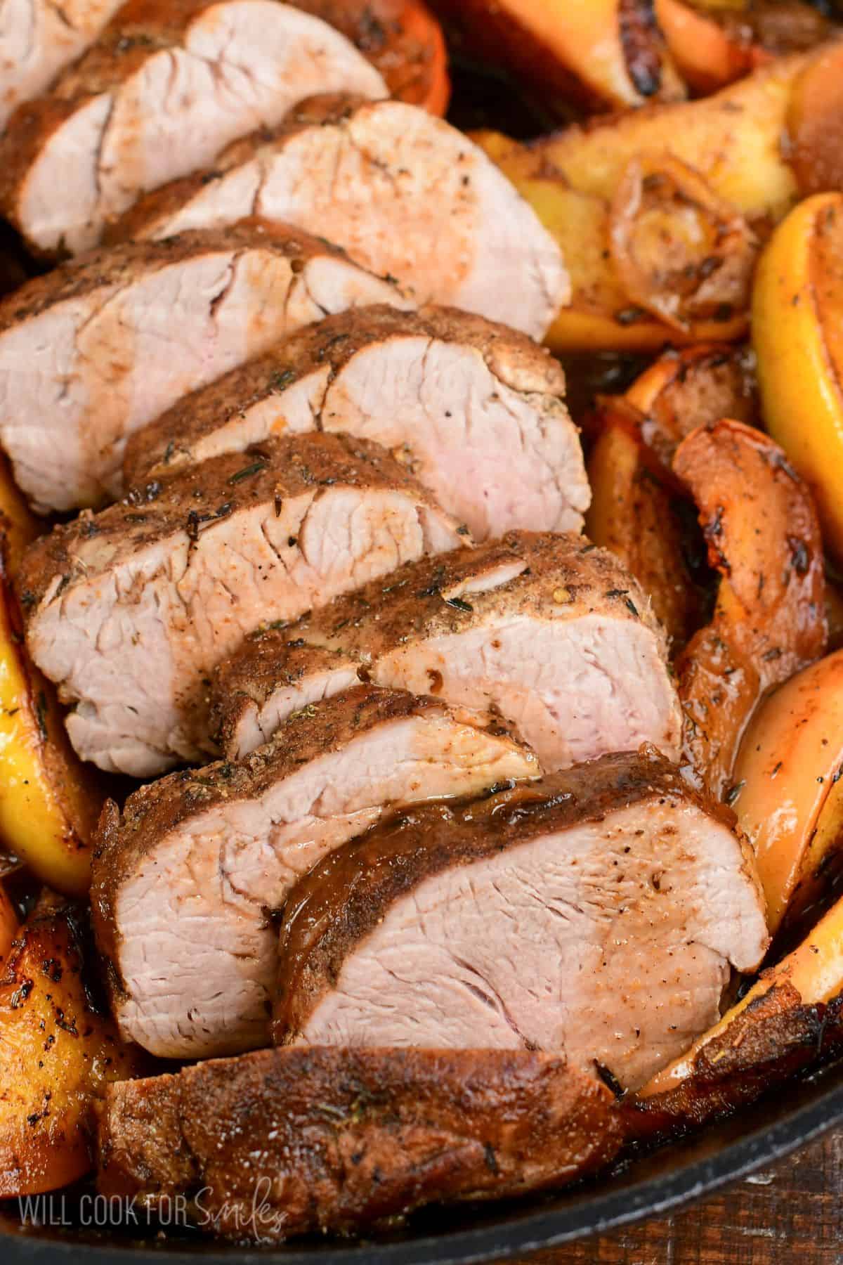 sliced roasted pork and apples in a cast iron skillet.
