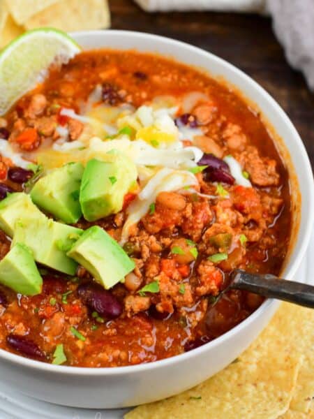 scooping out some turkey chili from a bowl with a metal spoon.