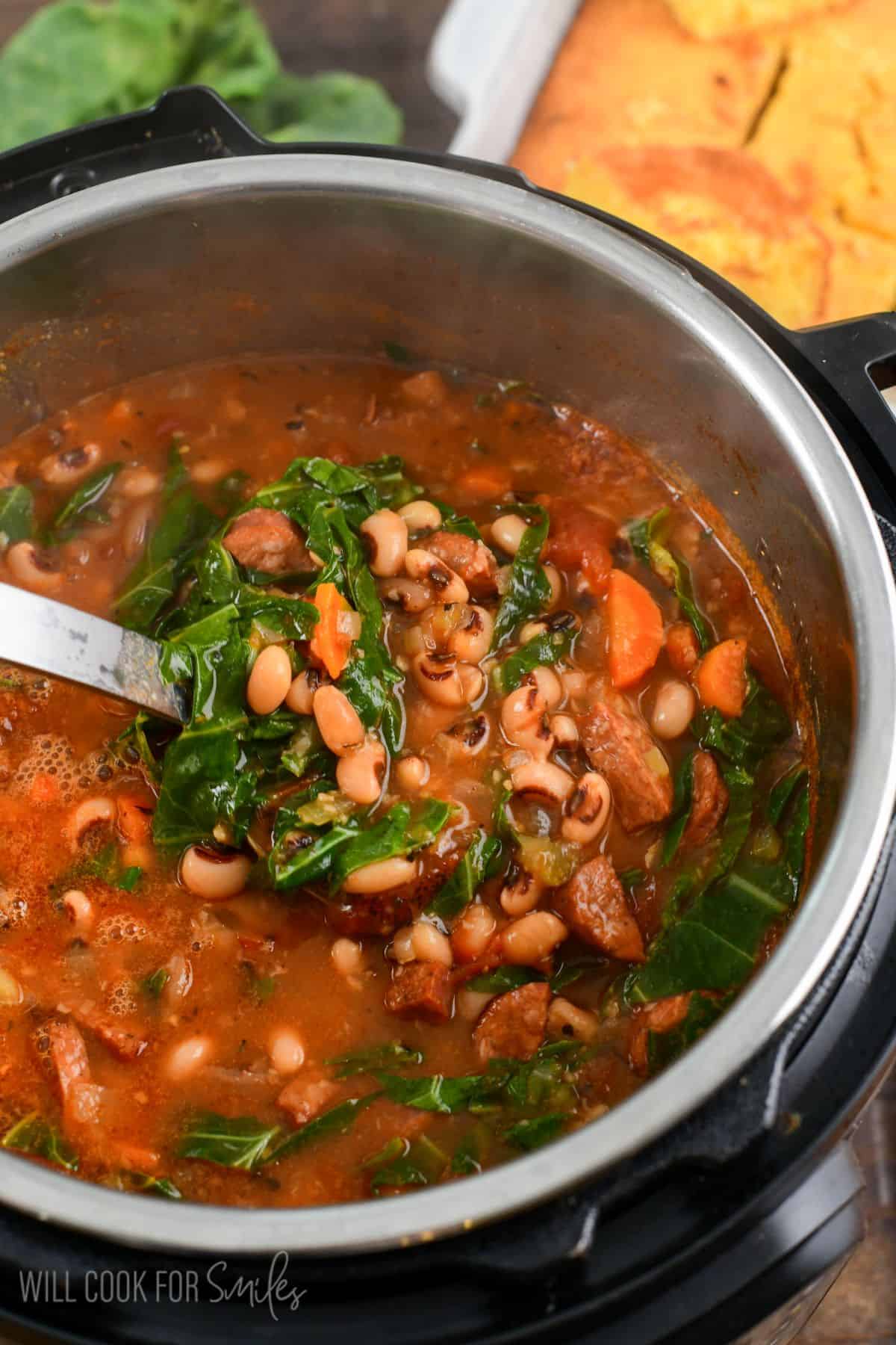 scooping out black eyed pea soup with sausage and collard greens from the Instant Pot next to fresh cornbread.