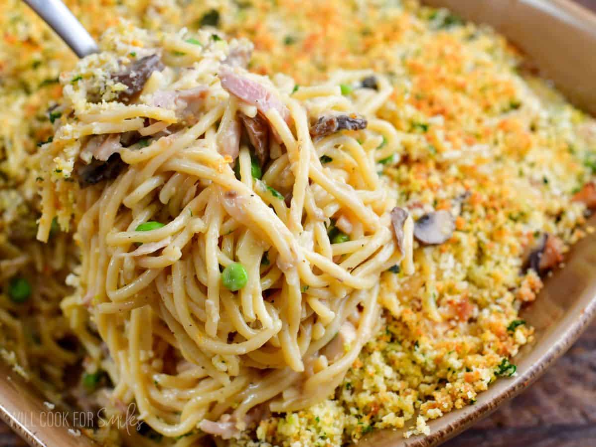 Scooping Turkey Tetrazzini out of casserole dish with a fork.