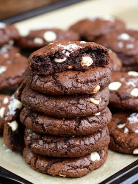 Chocolate brown butter cookies stacked up and the top cookie has been broken in half.
