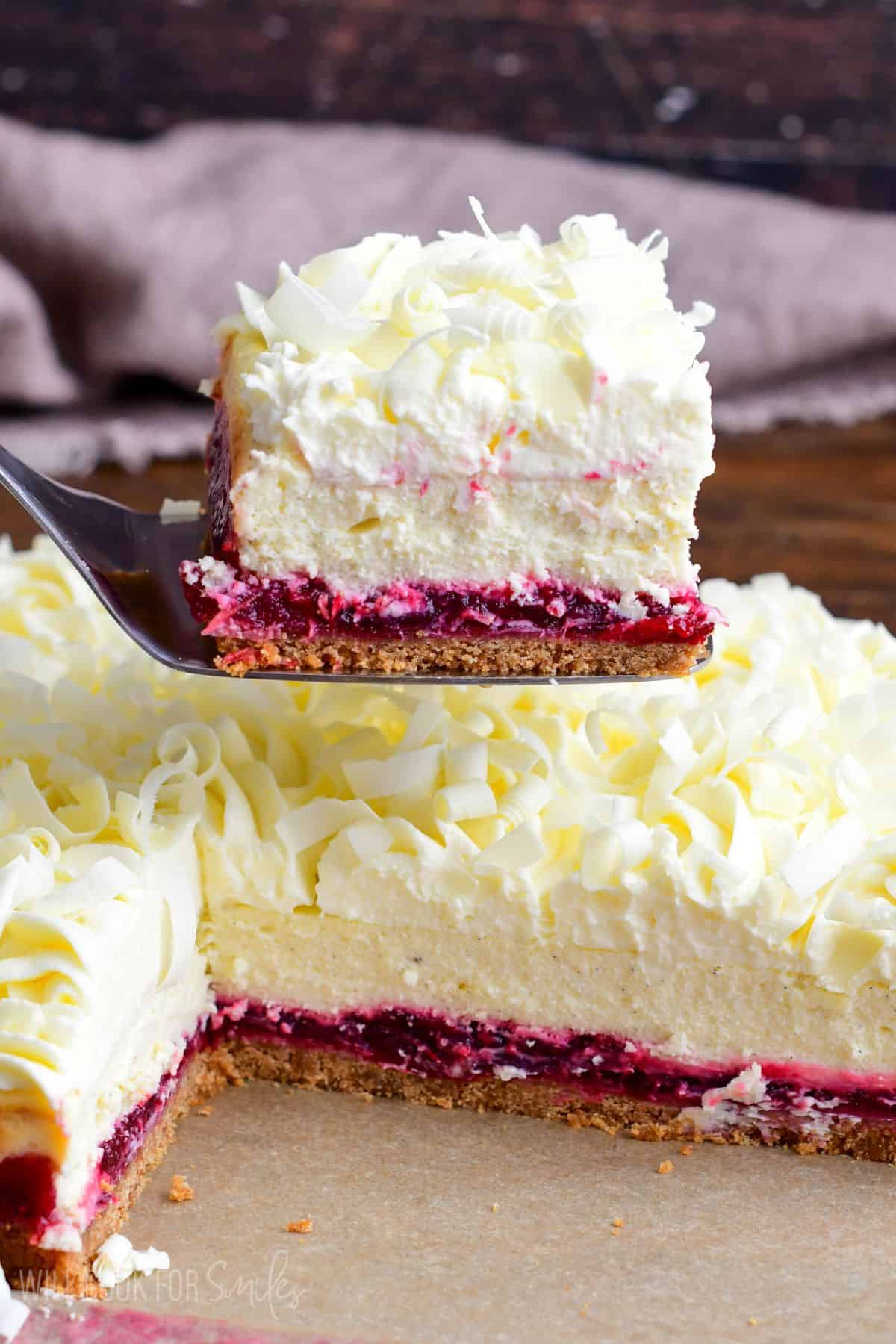 Christmas Cheesecake bar on a spatula with the rest of the bars uncut on the table.