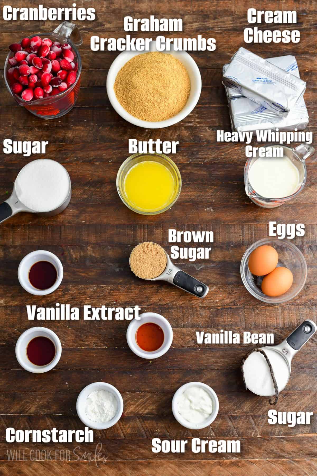 labeled Christmas Cheesecake bars (White Chocolate Cranberry Cheesecake Bars) ingredients on a wood surface.