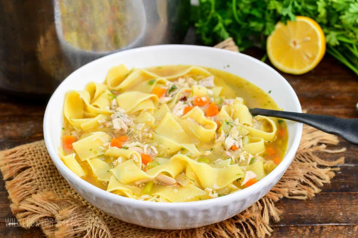Bowl of homemade chicken noodle soup with carrots, celery, and tender noodles with a spoon.