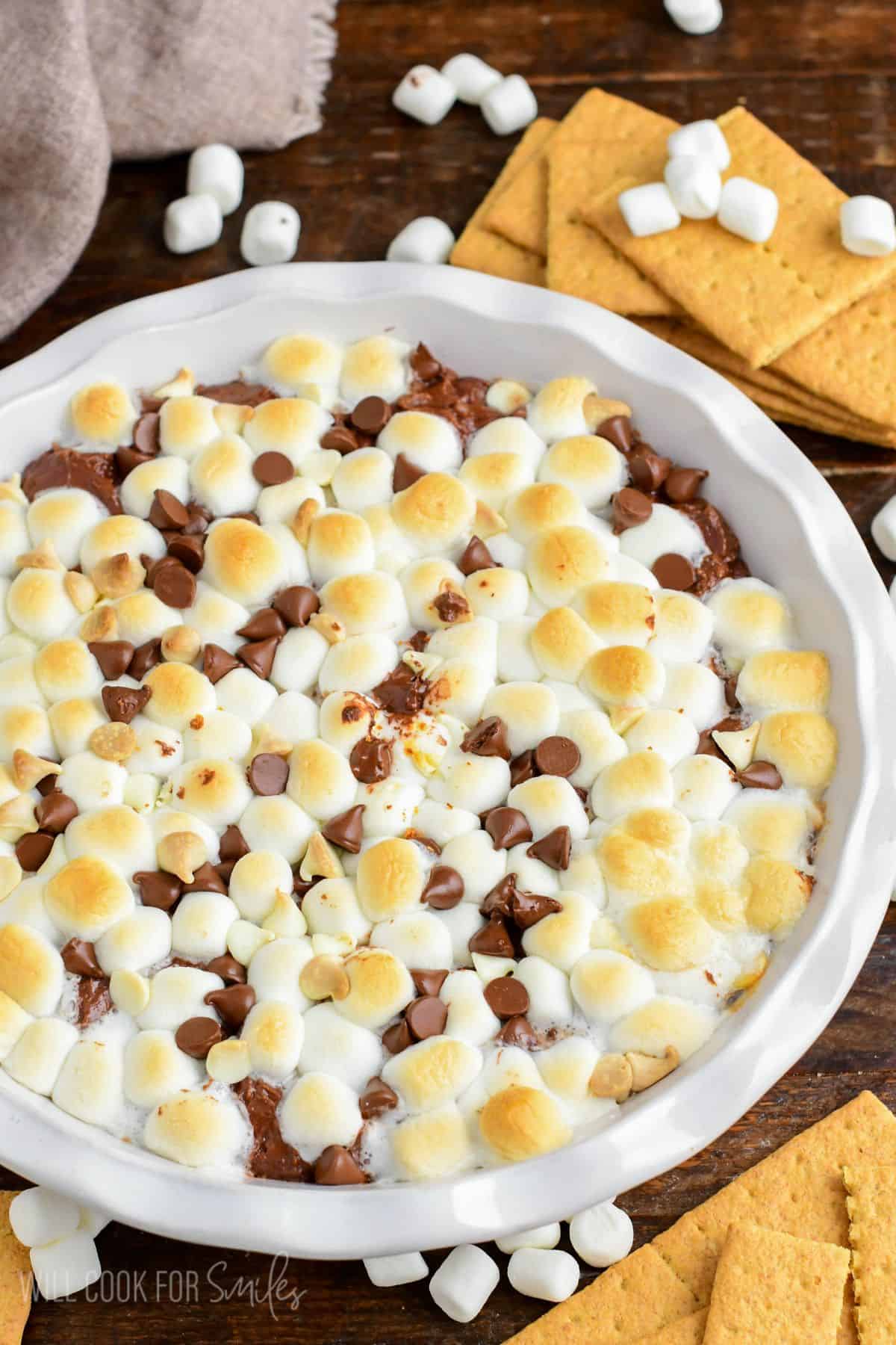 baked chocolate cheesecake dip topped with marshmallows and chocolate chips.