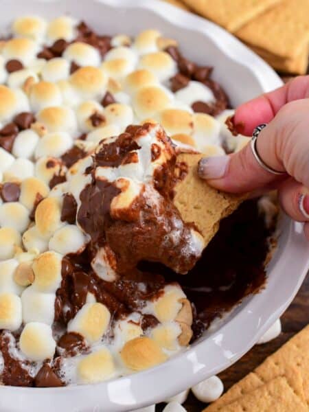 scooping out some warm and creamy chocolate cheesecake dip with gooey marshmallows.
