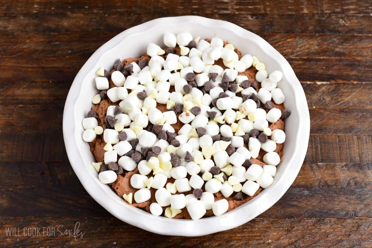 chocolate cheesecake mixture in the baking dish topped with marshmallows and chocolate chips.